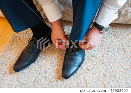 Young man tying elegant shoes indoors Young man tying elegant shoes indoors 47988403