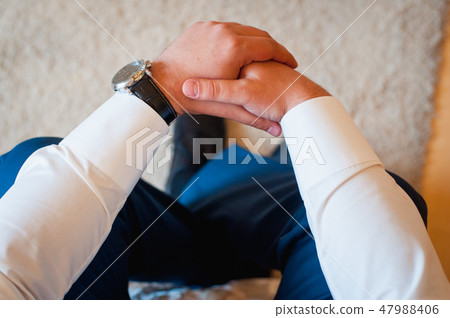 man sits with hands clasped man sits with hands clasped 47988406