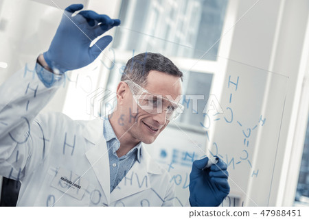 Smiling scientist figuring out new chemical formula Smiling scientist figuring out new chemical formula 47988451