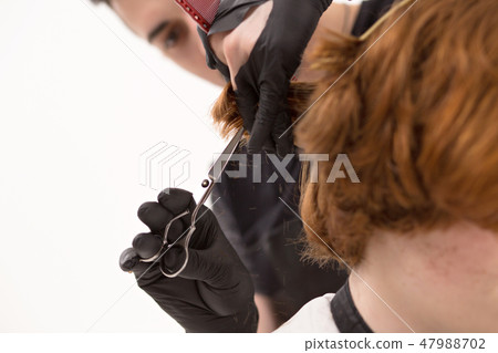 Close-up of barber trimming hair with scissors and comb 47988702