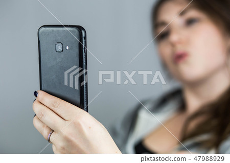 Teen girl taking selfie with duckface with her mobile phone Teen girl taking selfie with duckface with her mobile phone 47988929