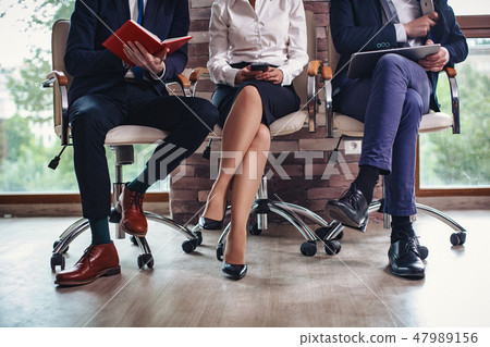Crossed legs of business people sitting in a row Crossed legs of business people sitting in a row 47989156