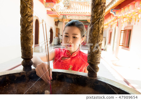 Asian Chinese woman praying with incense sticks Asian Chinese woman praying with incense sticks 47989654