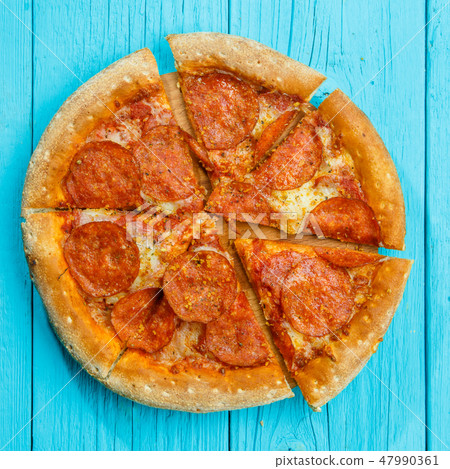 Pizza on a blue wooden table. 47990361