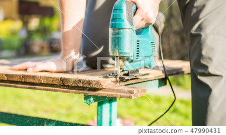 Worker with electric jig saw 47990431