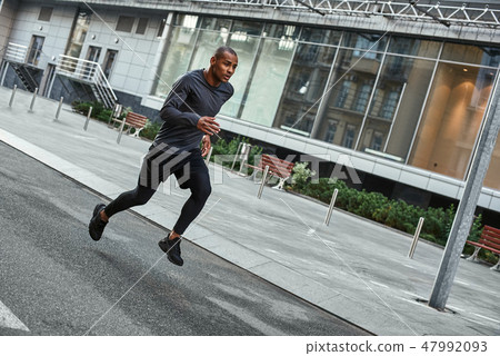 Confident runner. Full length portrait of athletic african man in sportswear running with very fast Confident runner. Full length portrait of athletic african man in sportswear running with very fast 47992093