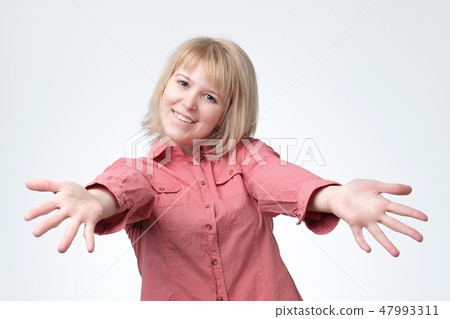 European woman in pink shirt with stretched hands handshake. She wants to hug her firends. 47993311
