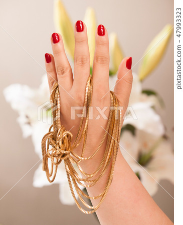 Hand with nice groomed nails holding gold jewels 47993323