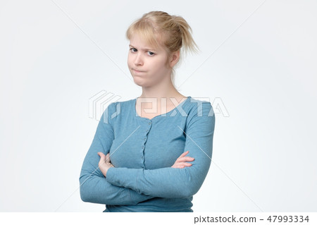 Upset unsatisfied blonde woman standing with arms folded Upset unsatisfied blonde woman standing with arms folded 47993334