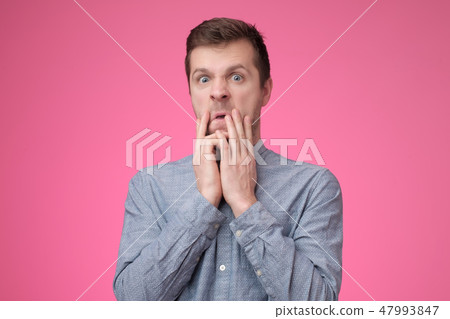 Displeased young male dressed in blue shirt, says fie and has dissatisfied facial expression 47993847