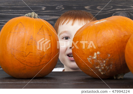 A little boy hid behind a pumpkin 47994224