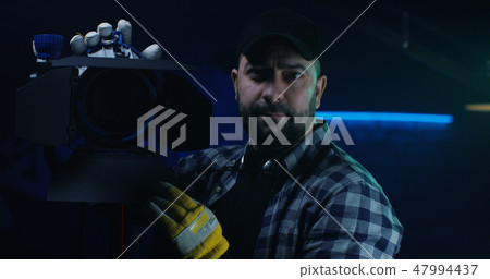 Cameraman holding a Fresnel lamp 47994437
