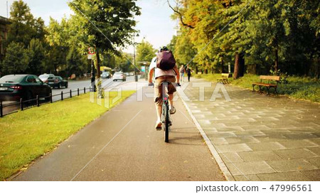 Unknown man cycling along urban bike path after summer rain 47996561