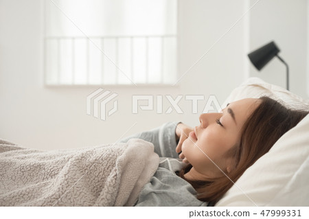 A woman sleeping in bed A woman sleeping in bed 47999331