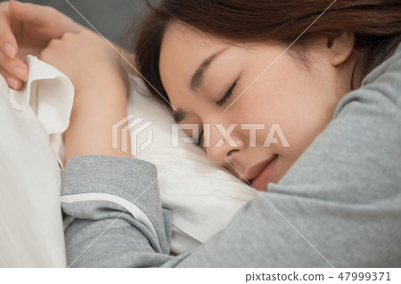 A woman sleeping in bed A woman sleeping in bed 47999371
