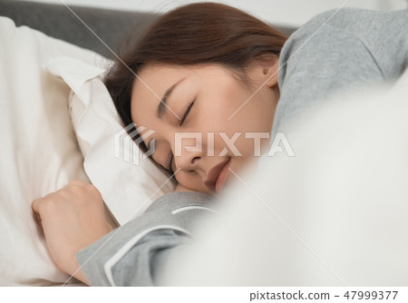 A woman sleeping in bed 47999377
