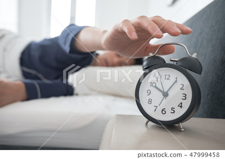 A man waking up in bed 47999458