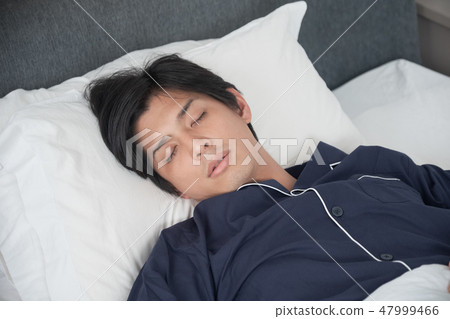 A man sleeping in bed 47999466