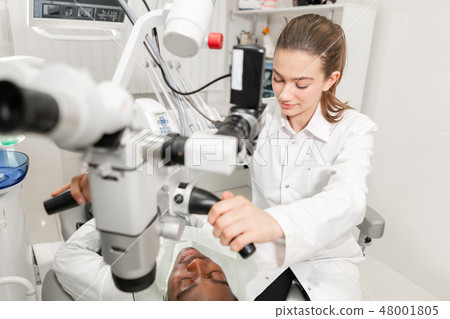 Female dentist advanced user, dental tools. Setup microscope for examining his patients teeth. in 48001805