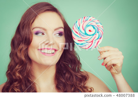 Smiling girl with lollipop candy on teal 48007388
