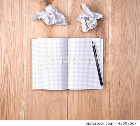 open notebook in a cell and a black wooden pencil 48009667