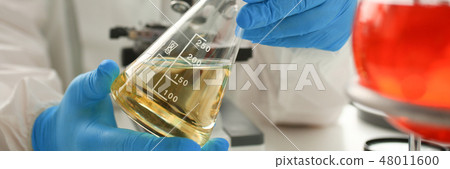 Male chemist look at microscope hold test tube Male chemist look at microscope hold test tube 48011600