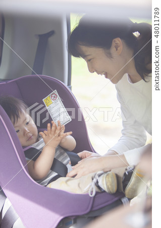 Mother sitting a child on a child seat 48011789