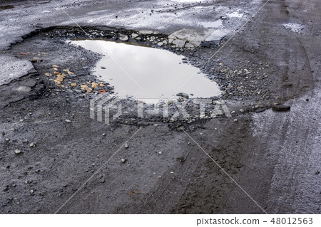 Bad asphalt road with pit and puddle 48012563