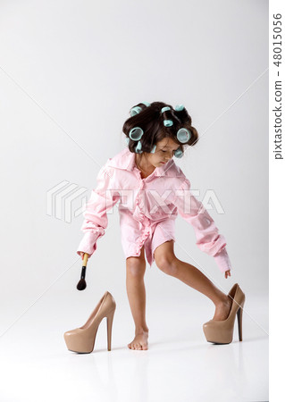 little girl playing with her mother's clothes and shoes 48015056