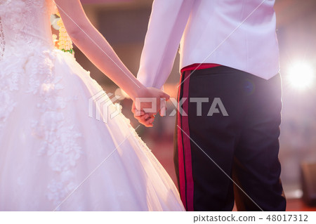Man and woman holding hands in wedding ceremony Man and woman holding hands in wedding ceremony 48017312