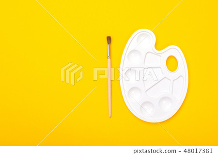 Paint brush and palette lie isolated on yellow background Paint brush and palette lie isolated on yellow background 48017381
