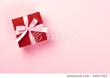 Red gift box with pink ribbon on pink background. 48017403