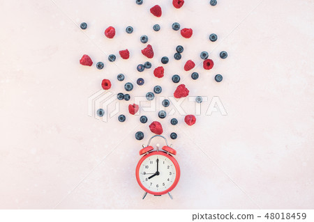 Composition with berries and red alarm clock Composition with berries and red alarm clock 48018459