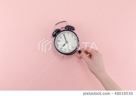 Female hand with alarm clock. Morning concept Female hand with alarm clock. Morning concept 48018530