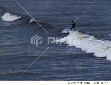 Surfer holding oar negotiating waves in Tynemouth Surfer holding oar negotiating waves in Tynemouth 48018643