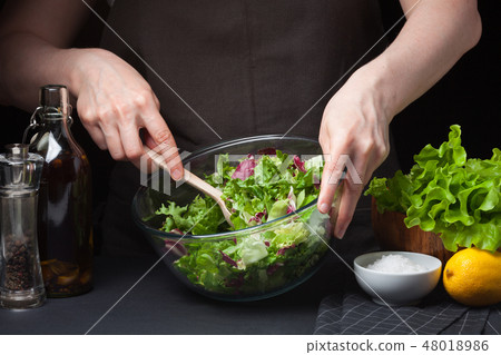Woman chef in the kitchen preparing salad. 48018986