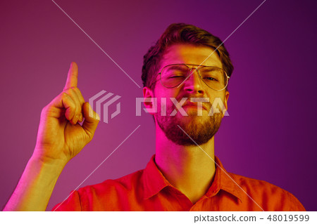 Suspiciont. Doubtful pensive man with thoughtful expression making choice against neon background Suspiciont. Doubtful pensive man with thoughtful expression making choice against neon background 48019599