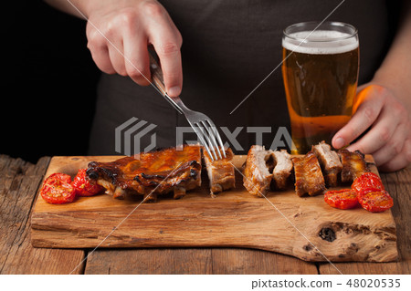 chef skewers with a fork ready to eat pork ribs. 48020535