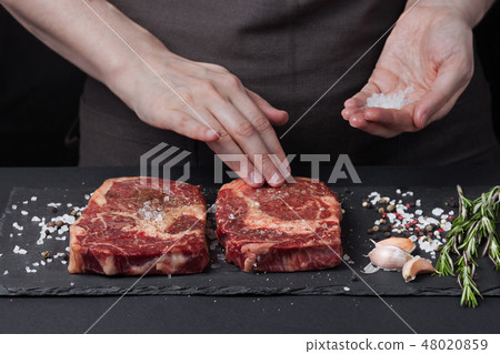 The woman chef is preparing a beef steak. 48020859