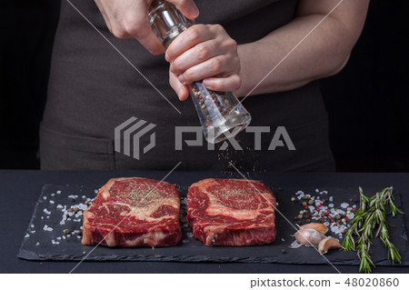 The woman chef is preparing a beef steak. 48020860