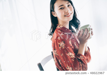 A red one-piece lady sitting in a chair with a mug 48022967