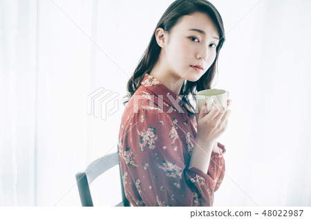 A red one-piece lady sitting in a chair with a mug 48022987