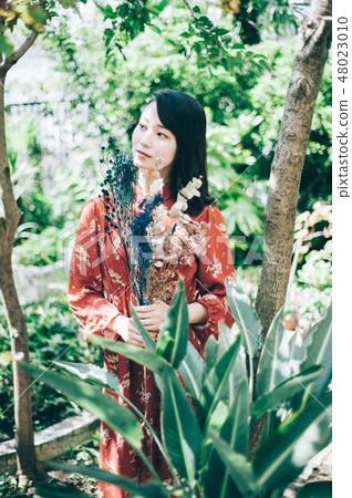 A red one-piece lady with a bouquet in the garden 48023010