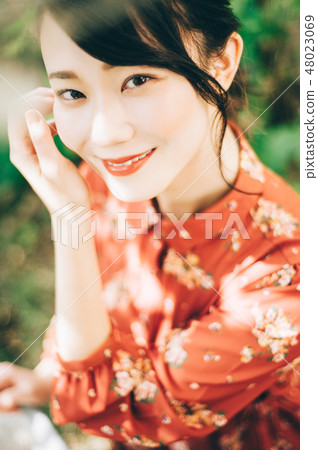 A red one-piece lady up in the garden with hair up A red one-piece lady up in the garden with hair up 48023069