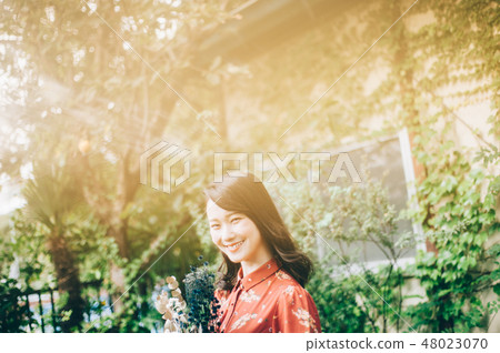 A red one-piece lady with a bouquet in the garden A red one-piece lady with a bouquet in the garden 48023070