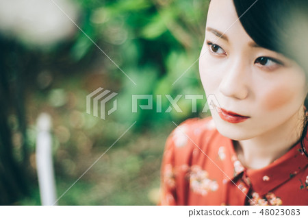 A red one-piece lady up in the garden with hair up 48023083