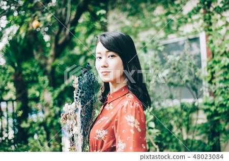 A red one-piece lady with a bouquet in the garden 48023084