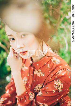 A red one-piece lady up in the garden with hair up 48023085