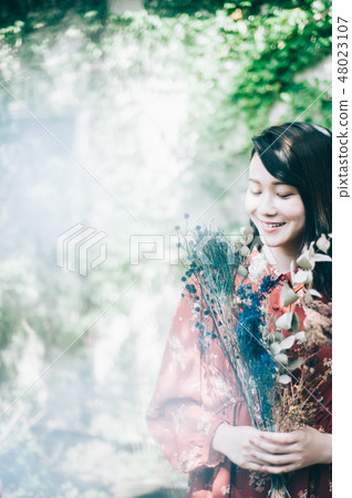 A red one-piece lady with a bouquet in the garden 48023107