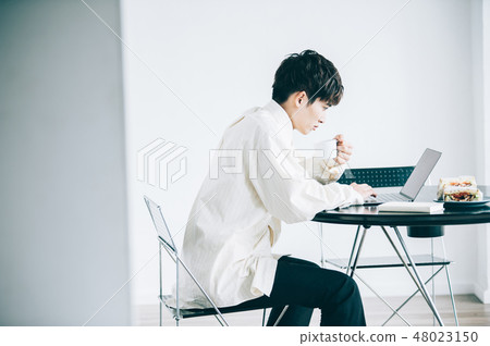 A man sitting in a chair and heading to a laptop 48023150